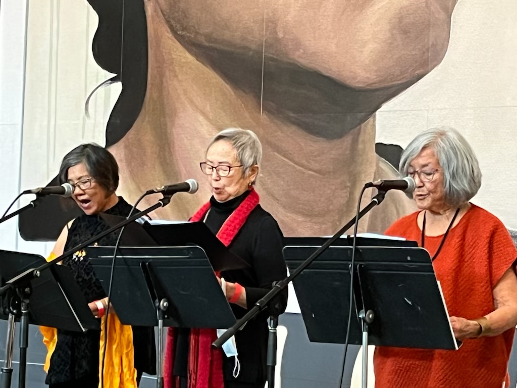 “American Born” poets Genny Lim, Flo Oy Wong and Nellie Wong, aka The Last Hoisan Poets, read their poem, “Dei Moy: Sisterhood is in the Heart” in front of Hung Liu’s large-scale mural/self-portrait, “Resident Alien” in the de Young Museum’s Wilsey Court.
