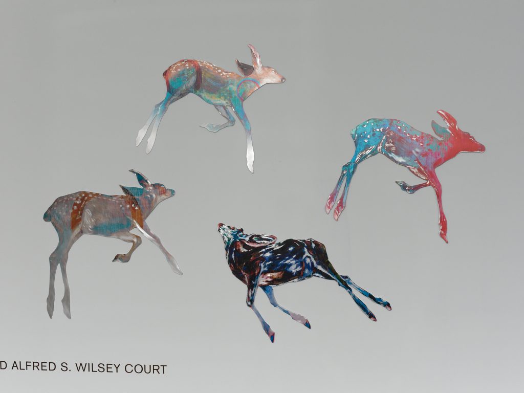 Hung Liu’s colorful deer leap in a circular never-ending dance on the white walls of the de Young Museum’s Wilsey Court.